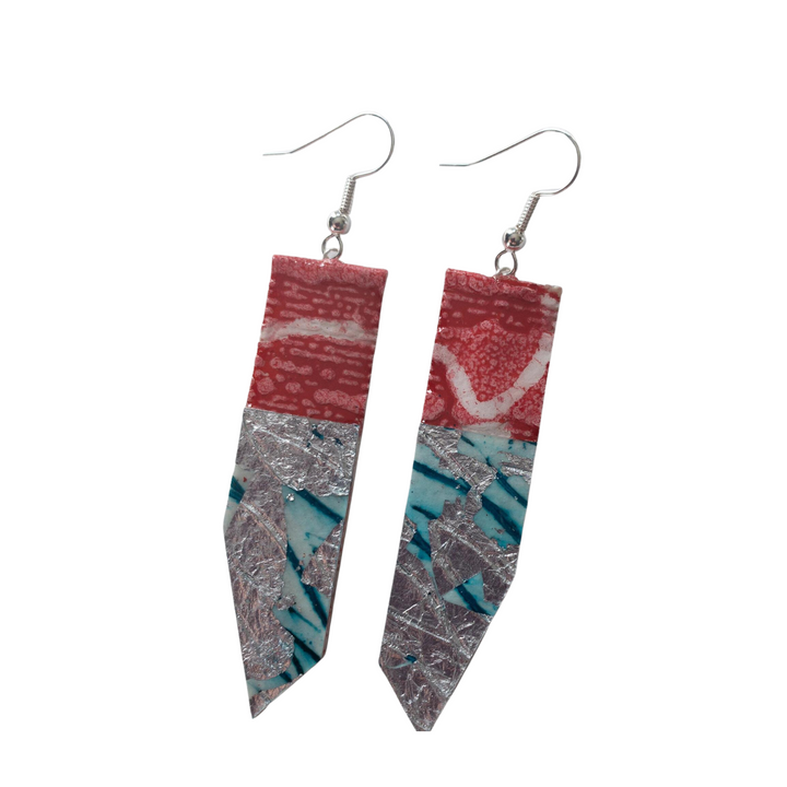 A pair of one-of-a-kind, handmade Edythe Batik Textile Earrings in Poppy/Silver/Aqua from Rothlú featuring long, geometric shapes. The earrings have a color-block design with sections of pink, teal, and silver patterned areas. They hang from simple metal hooks and are super-lightweight for all-day wear.