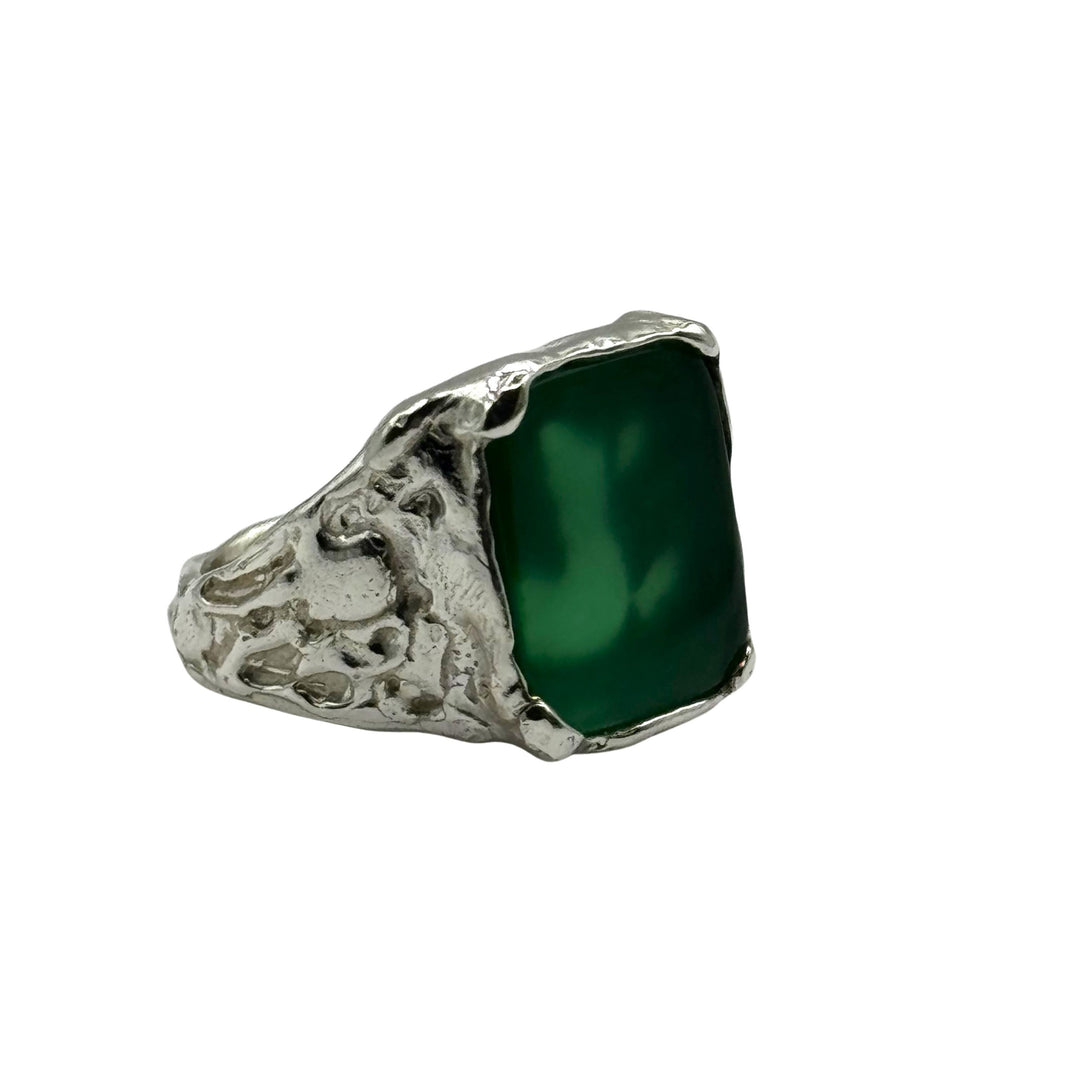 The Essence Silver Ring by Inó Jewellery features a raw silver band with an organic texture and a smooth rectangular green gemstone, creating an elegant contrast between the polished stone and the artisanal finish.
