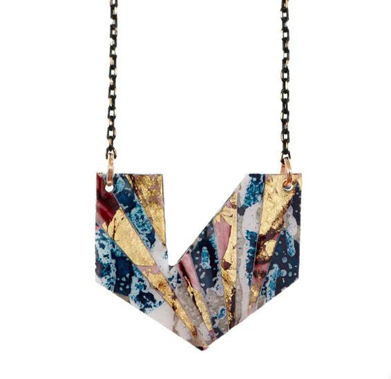 The Rothlú Ezrine Batik Textile Necklace in Teal/Red/Gold features a hand-formed, V-shaped geometric pendant with abstract patterns and a layered texture on a black chain, finished with eco resin.