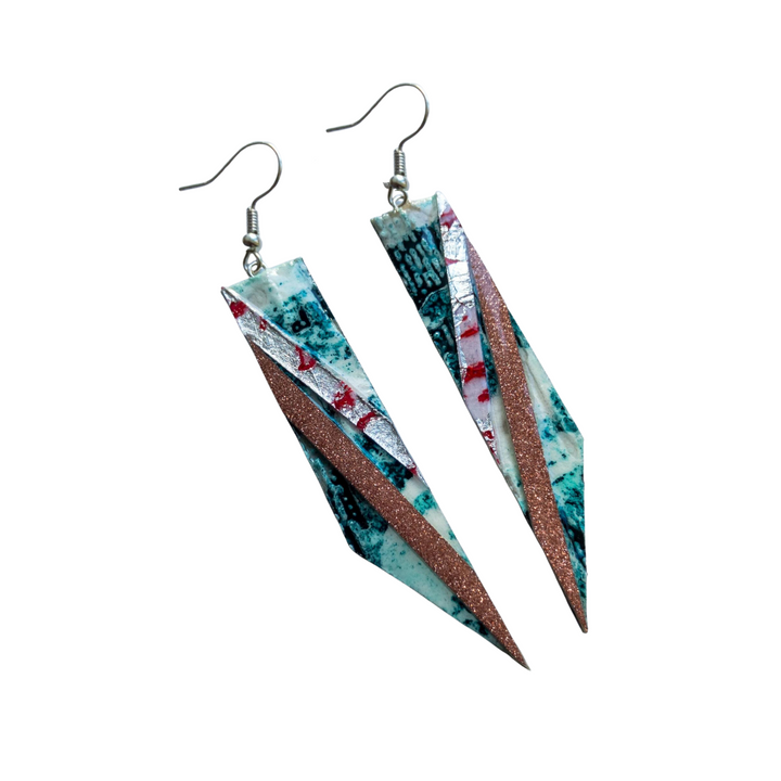 A pair of unique handmade jewelry earrings featuring an abstract design with blue, green, and red patterns. Each earring has a diagonal strip with a sparkly brown texture cutting through the middle. These Rothlú Foxtrot Batik Textile Earrings in Jade/Coral/Silver and Blush Shimmer complete the stunning look.