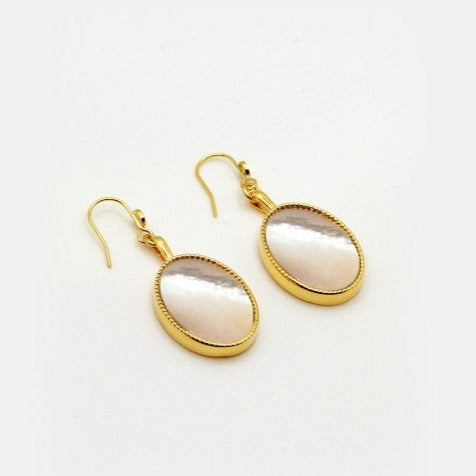 Introducing the Frida Earrings by Nilai, an elegant pair of gold drop earrings featuring oval-shaped, iridescent pearl-like insets. Handmade in Paris and finished with 24K gold, these sophisticated earrings are secured with gold hooks. Set against a plain white background, their simplicity and elegance shine through.