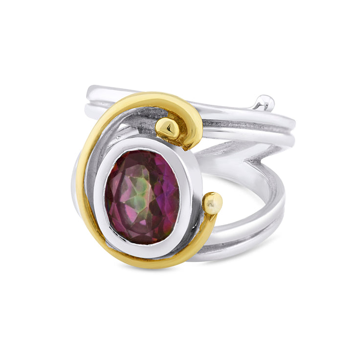 A silver Art Nouveau ring featuring an oval, faceted, multicolored gemstone set in the center. The gemstone is encircled by a gold swirl design that wraps around the adjustable band, creating an elegant and modern look. This exquisite piece is called the Jasmine Ring in various gemstones from Gallardo & Blaine Designs.