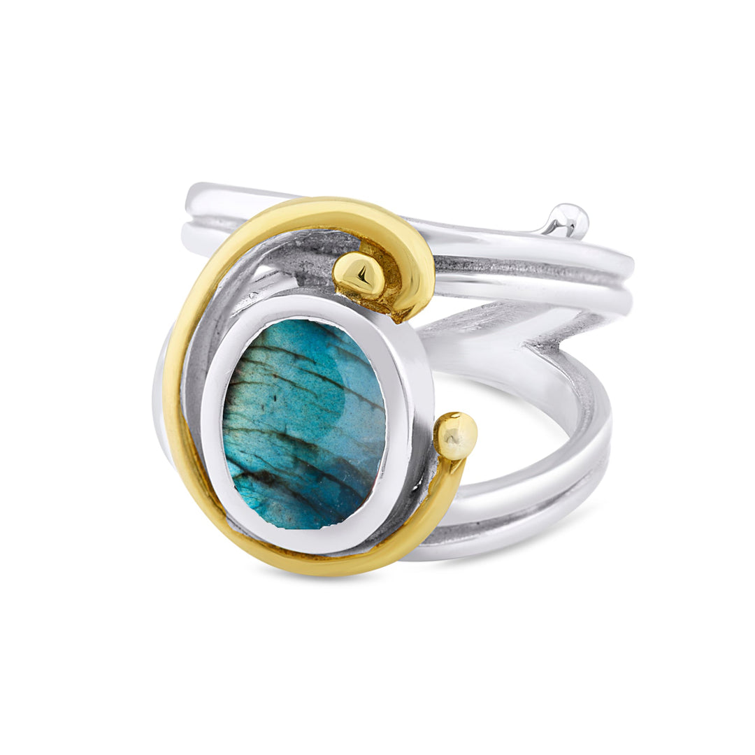 A silver and gold Jasmine Ring in various gemstones by Gallardo & Blaine Designs featuring an oval-shaped, polished blue-green stone set in a swirl design. The band is silver with a smooth finish, accented by a gold loop encircling part of the stone. The intricate design is contemporary and adjustable for perfect fit.