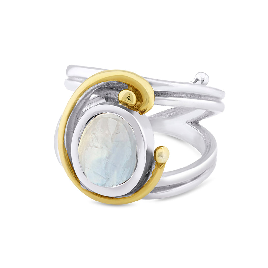 An elegant Jasmine Ring in various gemstones featuring an oval moonstone gemstone set in the center. Surrounding the stone is a distinctive gold swirl design that wraps around both sides of the band, adding a unique artistic touch. The wide, polished band beautifully highlights this exquisite piece of jewelry by Gallardo & Blaine Designs.