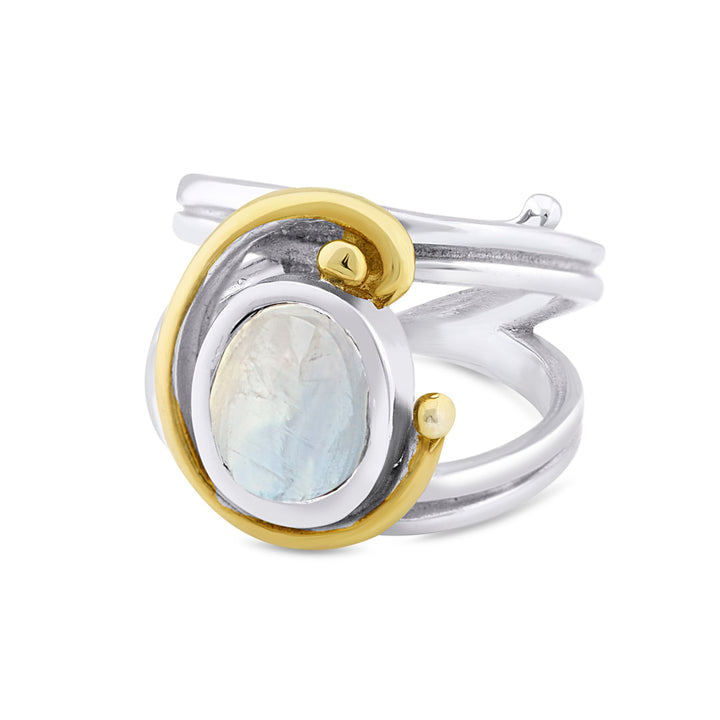 An elegant Jasmine Ring in various gemstones featuring an oval moonstone gemstone set in the center. Surrounding the stone is a distinctive gold swirl design that wraps around both sides of the band, adding a unique artistic touch. The wide, polished band beautifully highlights this exquisite piece of jewelry by Gallardo & Blaine Designs.