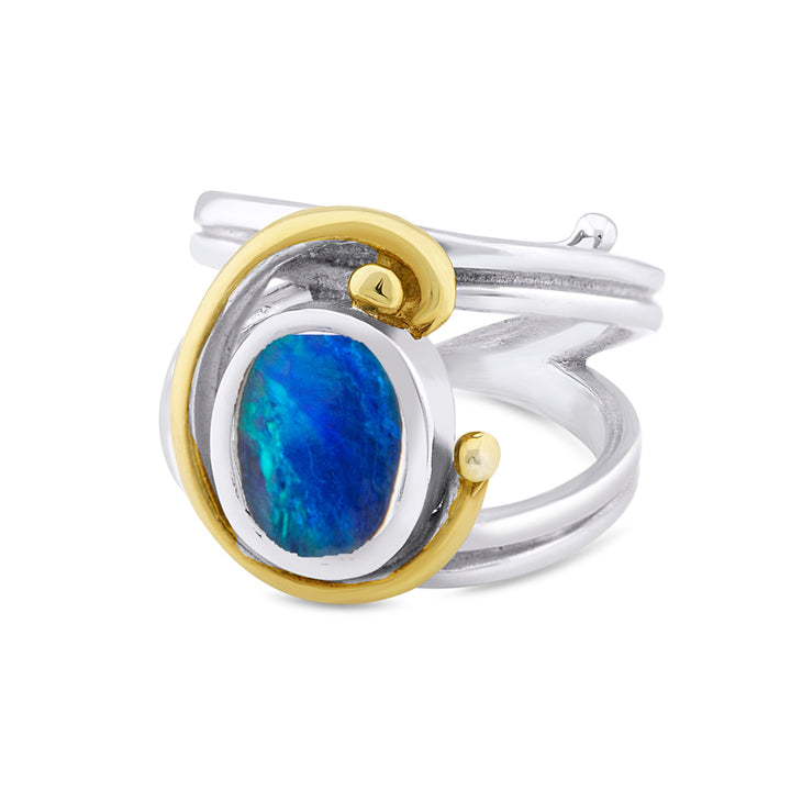 A **Jasmine Ring in various gemstones** by **Gallardo & Blaine Designs** is shown. It has a central oval blue gemstone accentuated by a surrounding gold swirl. The ring's design combines both smooth and textured metal elements, blending modern and classic styles seamlessly.