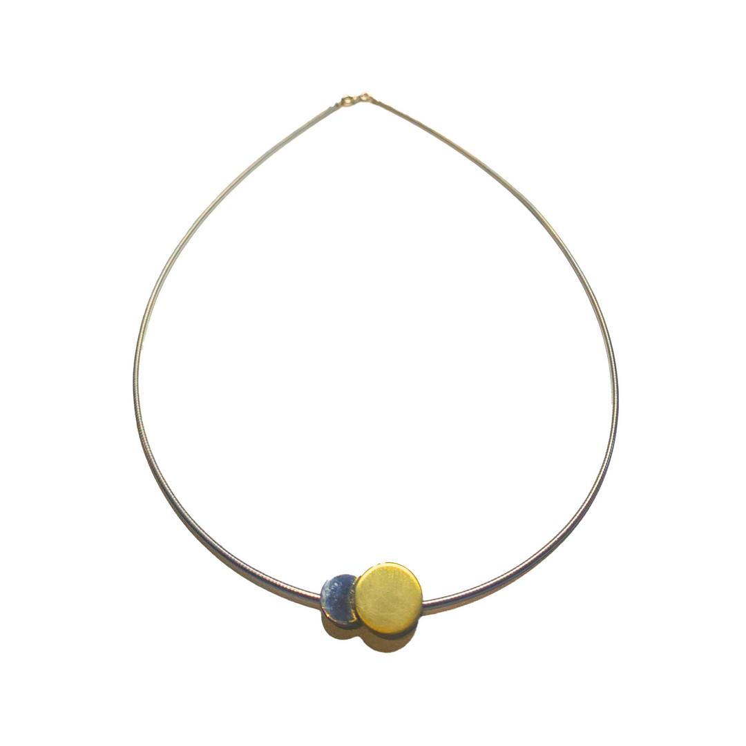 The Archeol Necklace in Sterling Silver & Gold Vermeil by Gallardo & Blaine Designs is a minimalist piece featuring a thin, sterling silver chain with two circular pendants: one blue and one gold vermeil. The blue pendant is slightly smaller and overlaps the gold pendant. It elegantly displays against a white background.