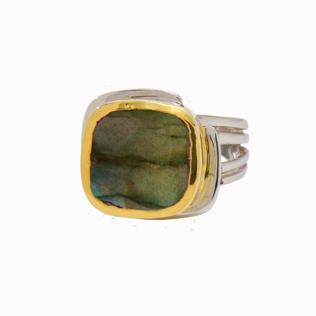 A Gallardo & Blaine Designs Art Deco Ring in Silver Gold & various gemstones featuring a square-shaped labradorite gemstone with a golden bezel setting. The labradorite displays greenish-blue hues. The Art Deco-inspired band has multiple silver strands merging at the base. The background is plain white.