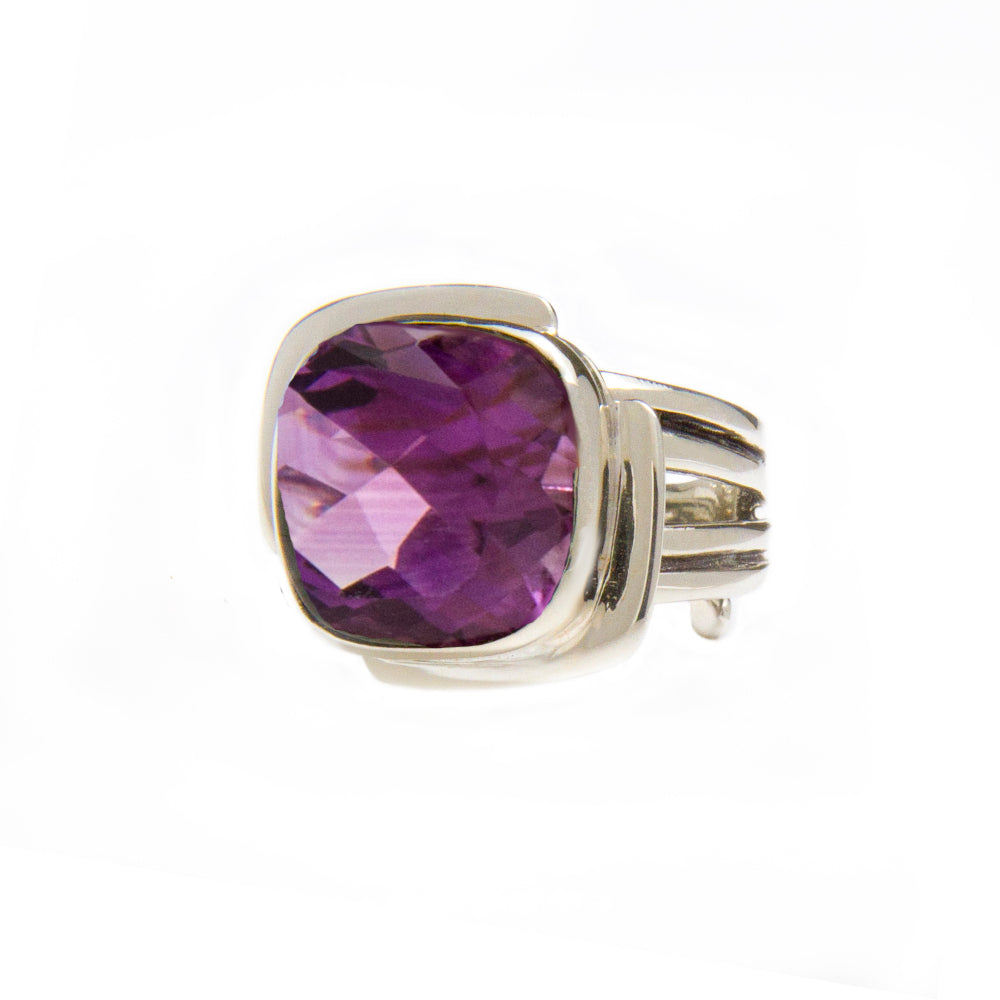 A sterling silver ring featuring a large, square-cut purple gemstone with a faceted surface. The band has a split design, adding to its intricate and elegant appearance reminiscent of an Art Deco ring. Displayed against a plain white background, this piece exudes timeless sophistication is the Art Deco Ring in Silver & Gold with various gemstones by Gallardo & Blaine Designs.