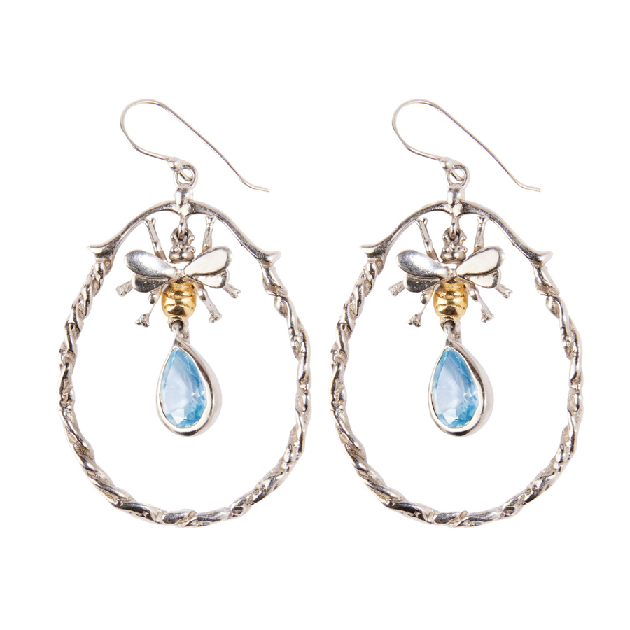 A pair of elegant Wildlife Large Bee Hoop Drops in various gemstones featuring intricate silver bees with gold-toned bodies. Each bee holds a teardrop-shaped blue gemstone drop, suspended within twisted sterling silver hoops. The earrings have hook-style clasps for easy wearing by Gallardo & Blaine Designs.