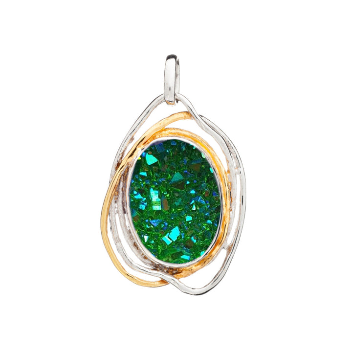 A Cosmos Pendant Large in various gemstones by Gallardo & Blaine Designs featuring a vibrant, emerald-green, oval-shaped gemstone with a druzy texture. The gem is set in a silver and gold intertwined metal frame, creating an elegant and artistic design reminiscent of medieval craftsmanship. The pendant has a small loop at the top for attachment to a chain.