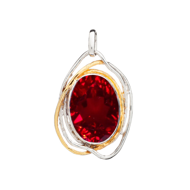 A Gallardo & Blaine Designs Cosmos Pendant Large in various gemstones featuring a large oval red gemstone encased in an intricate loop of silver and gold metal, forming a modern yet elegant design reminiscent of medieval artistry.