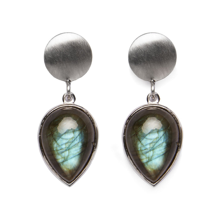 The Daira Earrings by Gallardo & Blaine Designs are a pair of elegant teardrop gemstone earrings featuring a brushed silver circular stud and a labradorite pendant. These colorful gemstones exhibit a play of colors, primarily green and blue, encased in shiny sterling silver.