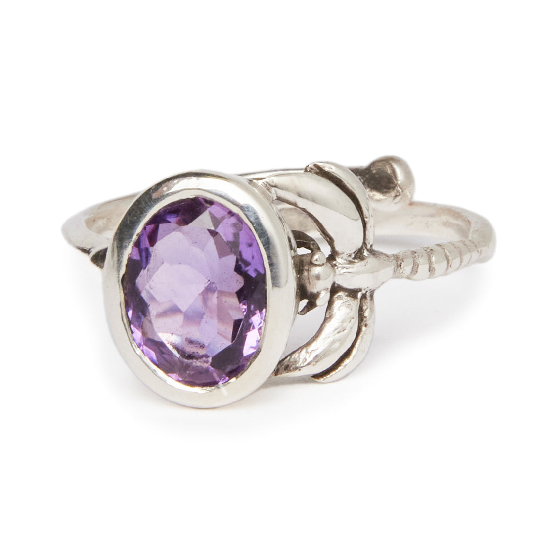 A timeless piece, the Daydream Ring in various gemstones by Gallardo & Blaine Designs features a large oval-shaped purple gemstone as its centerpiece. The band boasts ornate detailing resembling leaves around the gemstone setting, and its faceted cut ensures a reflective, sparkling appearance. This delicate and dainty ring is truly captivating.