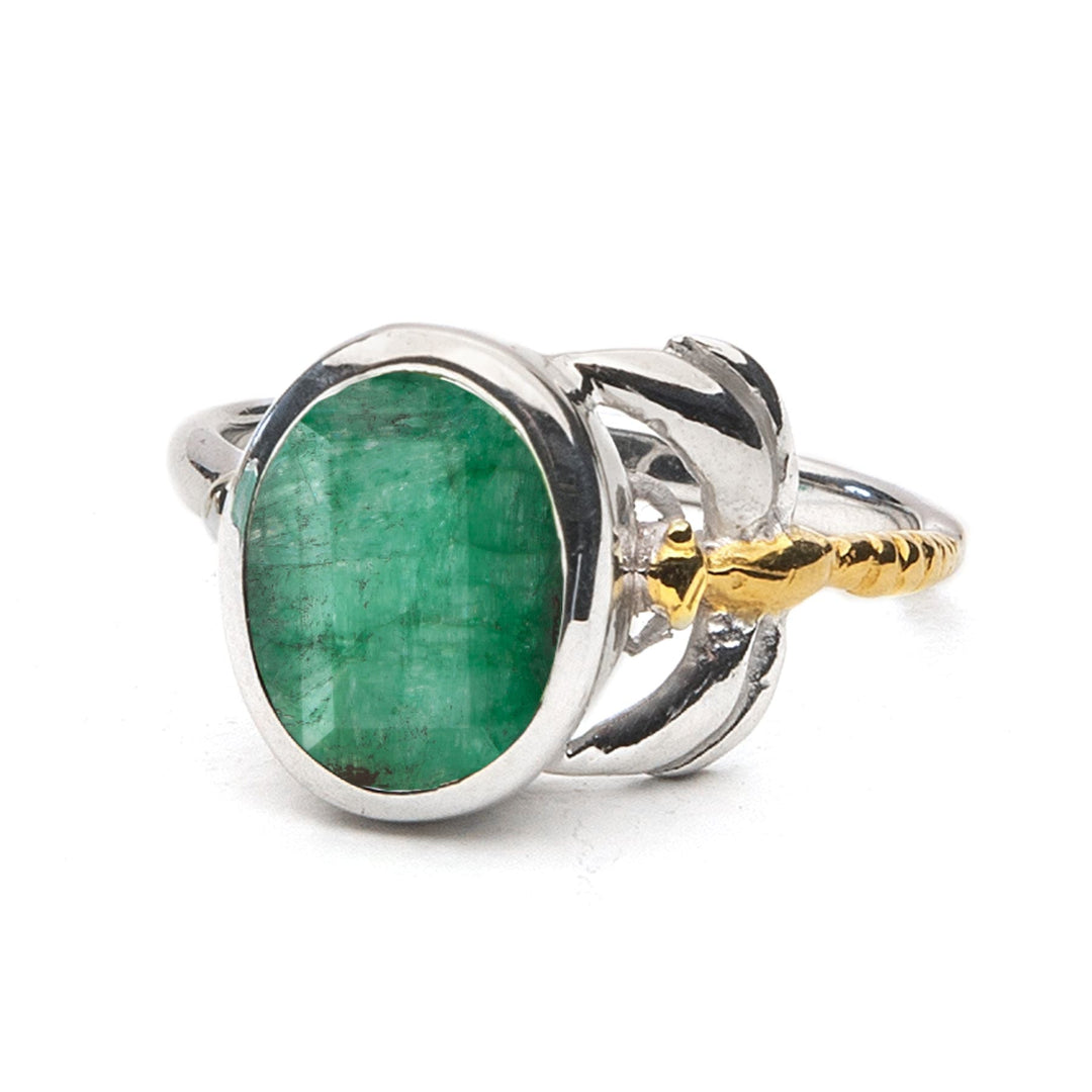 A Daydream Ring in various gemstones featuring a large, oval-shaped green gemstone set in the center by Gallardo & Blaine Designs. This timeless piece boasts intricate design elements, including a gold-toned accent on one side. The band has smooth, polished surfaces, making it a delicate and dainty addition to any collection.