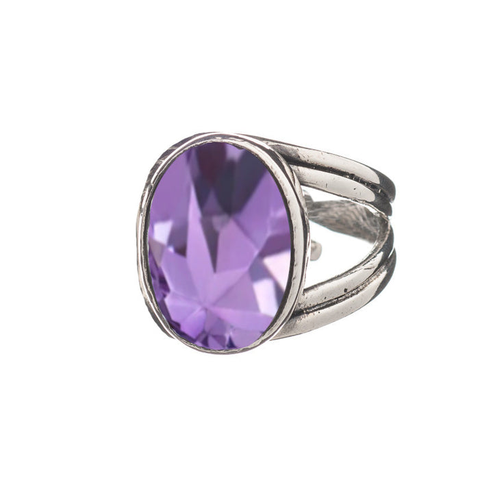 A Dewberry Ring in various gemstones by Gallardo & Blaine Designs featuring an oval-cut, faceted purple gemstone. The chunky statement ring is prominently set in a detailed silver band with a split shank design, giving the ring a bold and elegant appearance. The background is plain white.