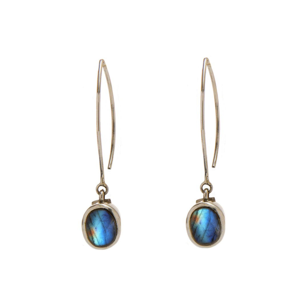 A pair of elegant Dew Drop Earrings in various gemstones featuring oval-shaped labradorite stones set in simple metal frames by Gallardo & Blaine Designs. The labradorite exhibits iridescent hues of blue and green. The earrings have thin, elongated hooks for easy wear. The background is plain and white.