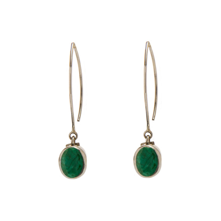 A pair of elegant Dew Drop Earrings in various gemstones by Gallardo & Blaine Designs featuring an elongated metal hook and an oval-shaped green gemstone set in a simple sterling silver frame. The earrings have a minimalist design, with the gemstone dangling from the bottom of each hook.