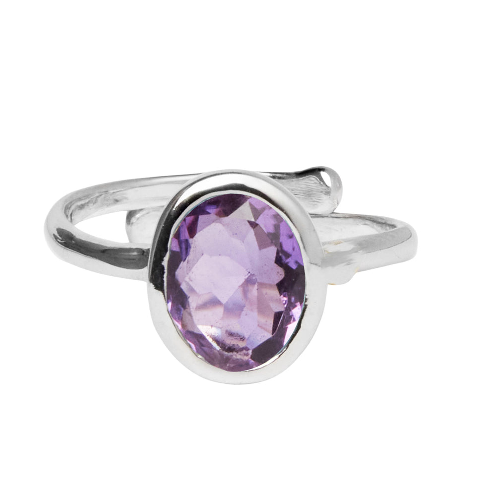 A Dream Ring in various gemstones by Gallardo & Blaine Designs with a prominent oval-shaped purple gemstone centerpiece. The band features a minimalist design, giving emphasis to the faceted gem.