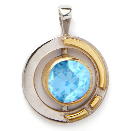 The Elodie Pendant in silver gold & various gemstones by Gallardo & Blaine Designs features a large, round, faceted blue gemstone at its center. Crafted from sterling silver and gold vermeil, the circular design incorporates two gold curved accents framing the gemstone for a modern and elegant Art Deco look.