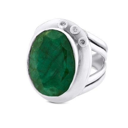 A statement cocktail ring featuring a large, oval-shaped green gemstone as the centerpiece. The gemstone is flanked by two small, round white stones on one side, set within a polished and sleek silver band with a split shank design. This adjustable design ensures a perfect fit for any finger. Introducing the Eyetelia Ring in various gemstones by Gallardo & Blaine Designs.