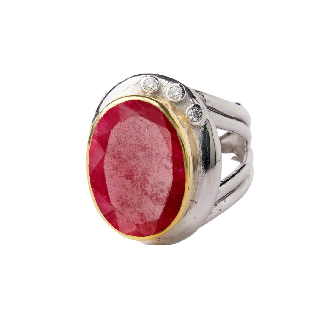 A statement **Eyetelia Ring in various gemstones** by **Gallardo & Blaine Designs** featuring a large oval-shaped red gemstone in a gold setting, flanked by three small round diamonds on the top of the band. This exquisite piece effortlessly combines colourful gemstones in a stunning design.