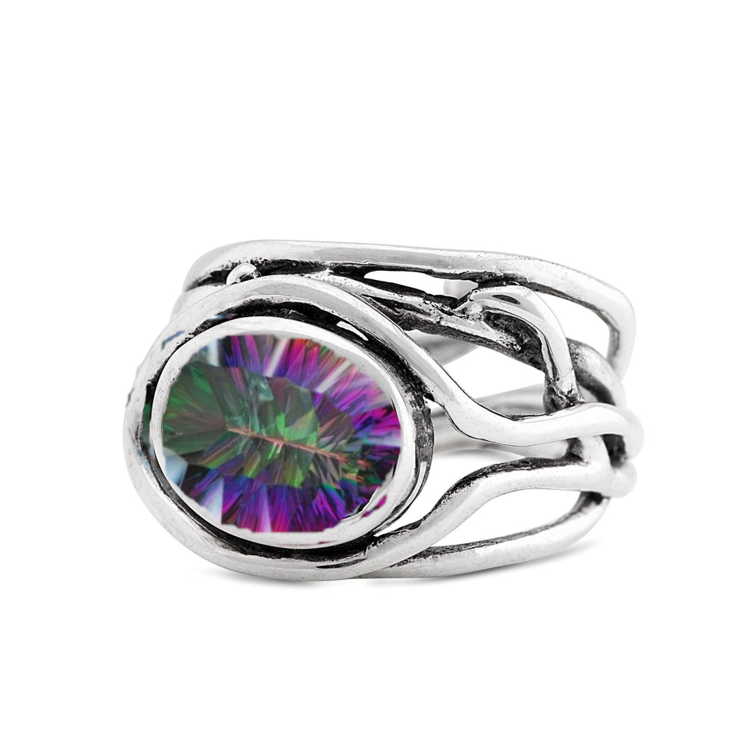 A unique **Fossil Ring in silver & various gemstones** featuring an intricate, twisting band design holding an oval-shaped, multicolored gemstone. The gemstone displays a range of colors including purple, green, and blue, and is the focal point of this artistic, organic-style gemstone ring by **Gallardo & Blaine Designs**.