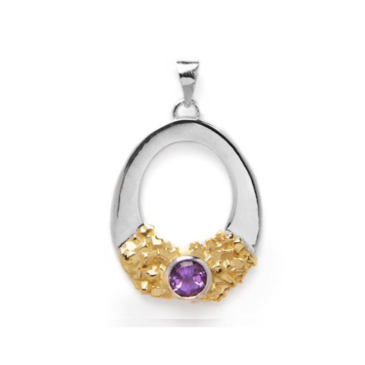 Introducing the Giselle Pendant from Gallardo & Blaine Designs: a stunning teardrop-shaped piece combining sterling silver and gold tones. The bottom half is elegantly adorned with gold accents and features a central, round purple gemstone. A smooth silver bail ensures easy attachment to any chain, making this an exquisite and eye-catching design.