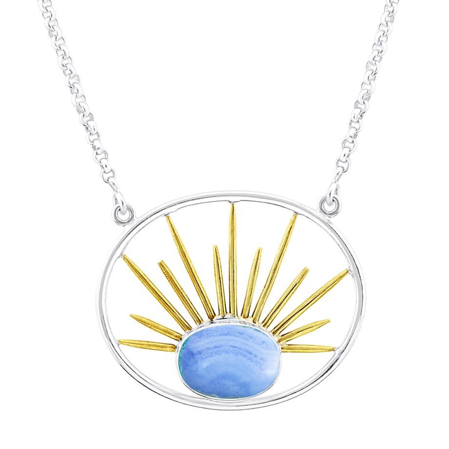 A silver necklace features a beautiful stone pendant. The Goddess Necklace Large in Various Gemstones by Gallardo & Blaine Designs is a circular silver frame with a blue gemstone at the bottom center, enhanced by gold vermeil spikes radiating from the gemstone, resembling a sunburst.