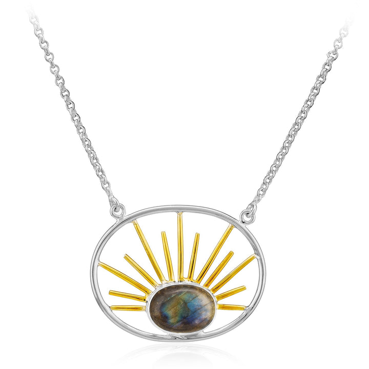 A silver necklace featuring a stone pendant with an oval-shaped multicolored gemstone. The gemstone is framed by an oval silver outline with gold vermeil radiating bars resembling sun rays extending outward from it, called the Goddess Necklace Large in Various Gemstones by Gallardo & Blaine Designs.