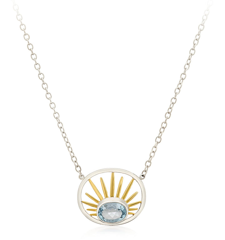 Introducing the Gallardo & Blaine Designs Goddess Necklace Small in various gemstones: a sterling silver creation featuring a dual-tone pendant on a delicate chain. The oval-shaped pendant showcases ascending gold rays, evoking a sunrise, while a light blue oval gemstone graces its base for an added touch of elegance.