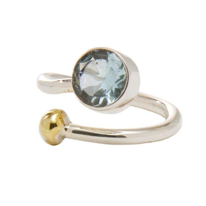 An elegant adjustable Honeysuckle Ring in Silver Gold & gemstones featuring a large, round, blue gemstone on one end and a small gold ball on the other, set in a silver band—perfect for those who appreciate silver and gold jewelry. This exquisite piece is brought to you by Gallardo & Blaine Designs.