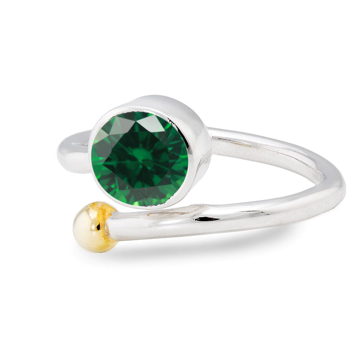 A silver and gold jewelry piece, the Honeysuckle Ring in Silver Gold & gemstones by Gallardo & Blaine Designs features an elegant adjustable gemstone ring design. It showcases a large round green gemstone on one end and a small gold bead on the other, highlighting its sleek and modern style against a white background.