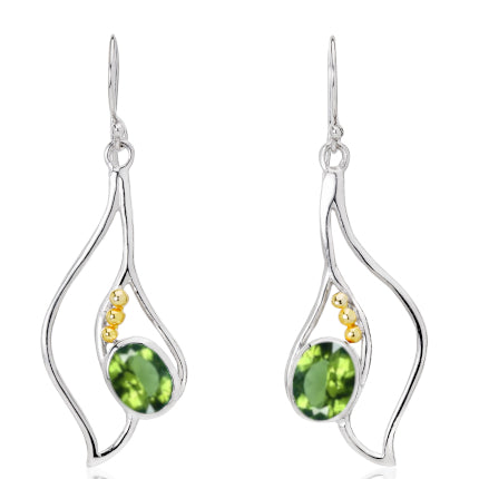 Introducing the Iris Earrings in various gemstones by Gallardo & Blaine Designs: a pair of elegant silver and gold earrings with a unique, abstract design. Each piece features an oval green gemstone surrounded by three small golden beads. The flowing, organic shape of the silver frame creates a modern and artistic look for any occasion.