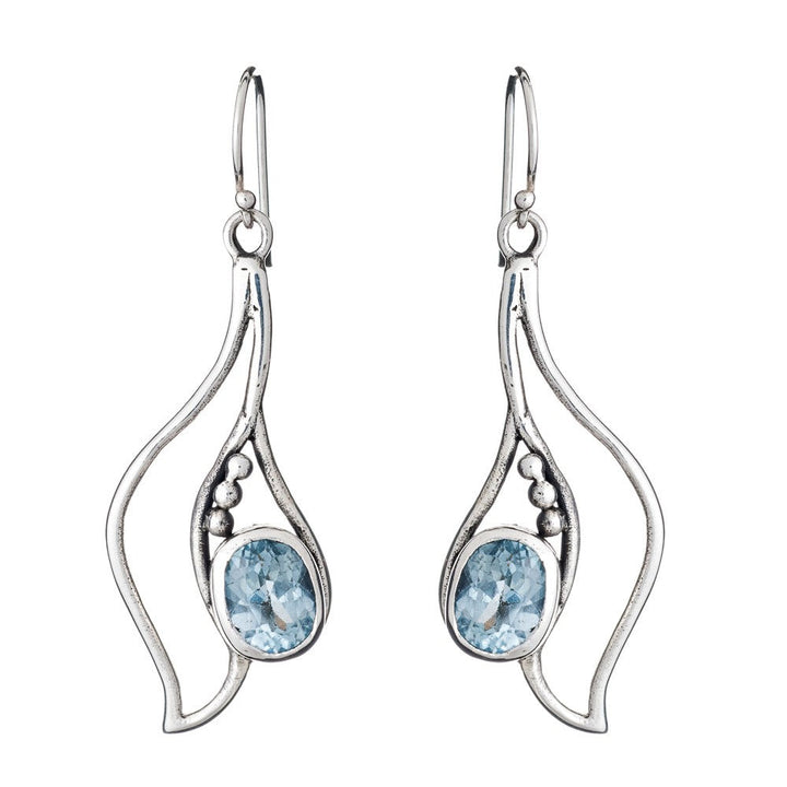 The Gallardo & Blaine Designs Iris Earrings in various gemstones feature wavy, abstract shapes crafted from silver & gold, adorned with oval blue gemstones. These elegant gemstone earrings have hook closures and are accented with small silver beads beside the gemstones.