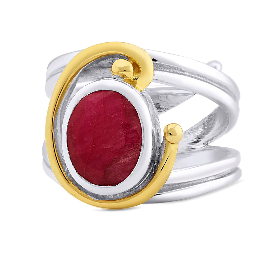 A silver Jasmine Ring in various gemstones by Gallardo & Blaine Designs featuring a large, oval-shaped red gemstone at its center, accentuated with a gold swirl design on one side and gold details. The band's design includes crisscrossing silver strands, giving it a modern and intricate appearance.