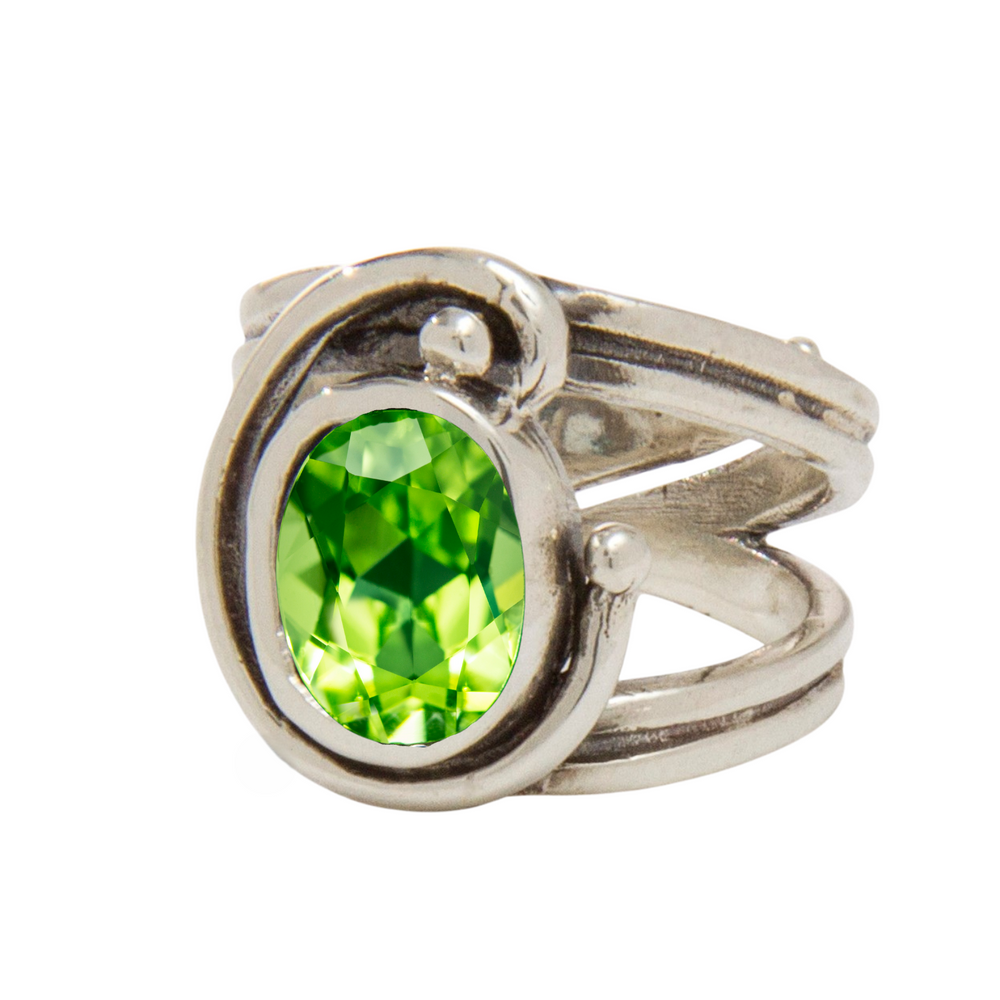 The Jasmine Ring by Gallardo & Blaine Designs features a unique, swirling sterling silver band and showcases a large, oval-cut bright green gemstone at its center.