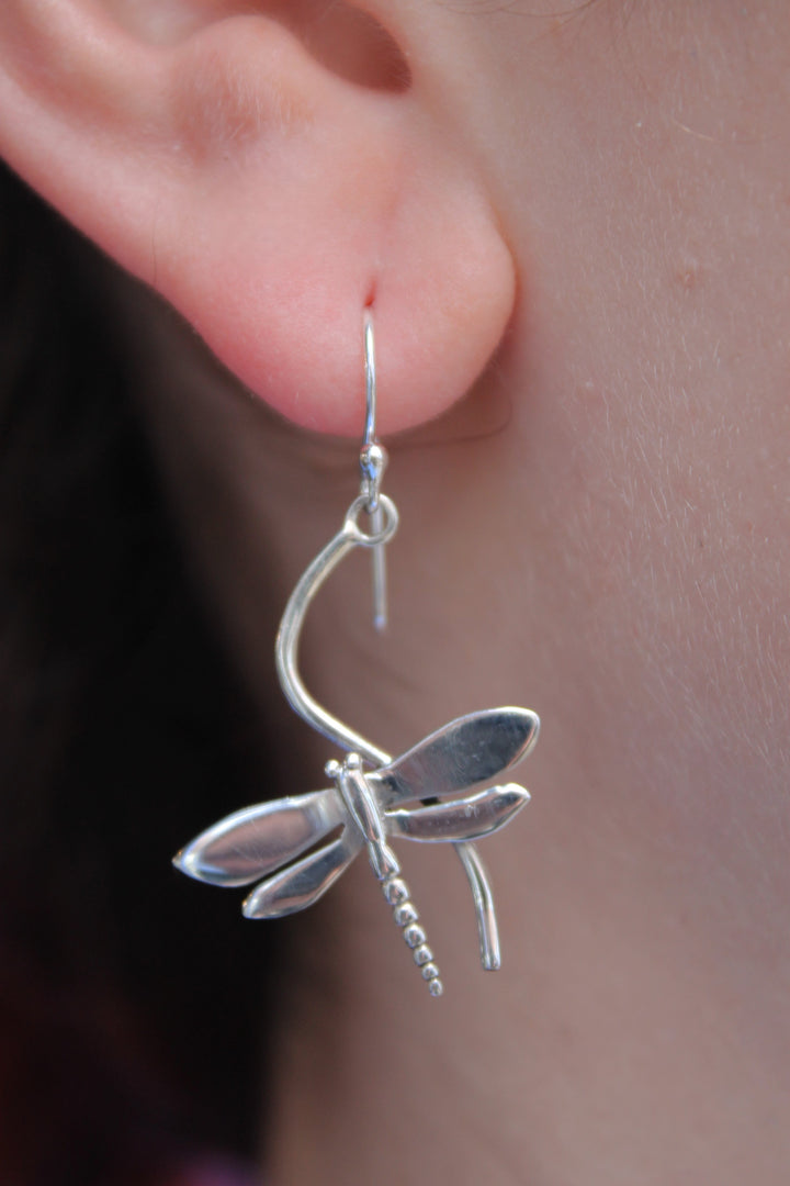 A close-up of a person's ear wearing Gallardo & Blaine Designs Wildlife Juniper Earrings (Silver or Gold), featuring intricate dragonfly wing and body details.