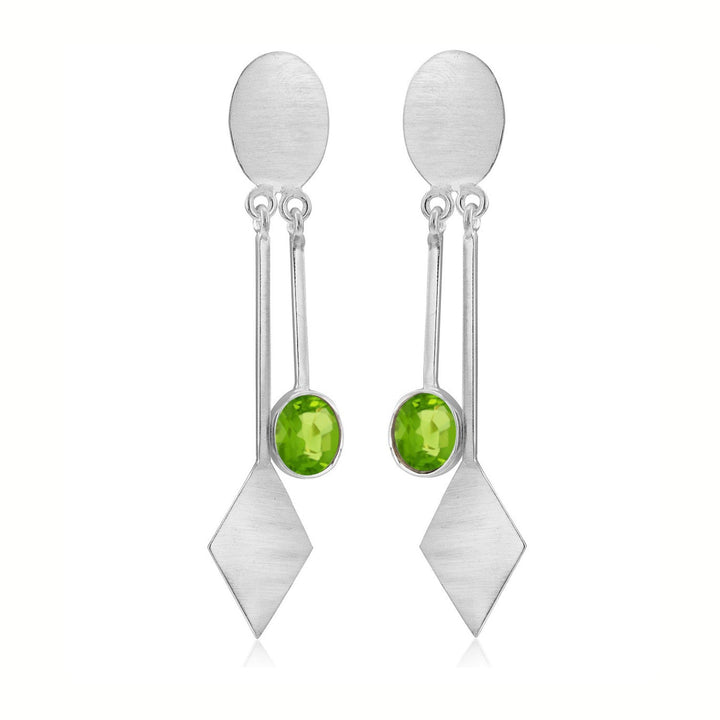 A pair of Karo Earrings in various gemstones by Gallardo & Blaine Designs. Each earring features an oval stud connected to a diamond-shaped pendant by a thin bar, with a single round green gemstone set in the middle section. The design is sleek and contemporary, perfect for modern fashion jewelry enthusiasts.