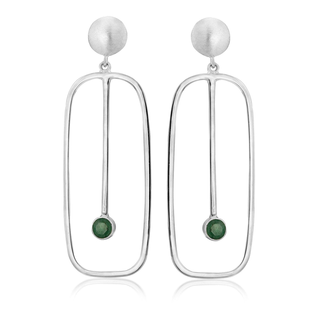 The Lorelei Earrings Large in various gemstones by Gallardo & Blaine Designs are a pair of elegant drop earrings featuring a matte-finish silver circular top, followed by an elongated open oval frame. Inside the frame, a vertical silver rod ends in a small round green gemstone, creating a minimalist and contemporary design.