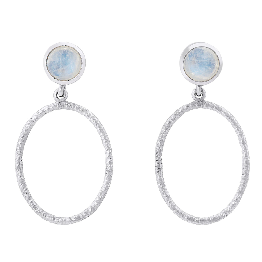 A pair of elegant Lunar Earrings in various gemstones by Gallardo & Blaine Designs featuring circular, textured hoops dangling from small round blue stone studs. The stones at the top have a soft, translucent appearance, adding a subtle touch of color to the minimalist design.