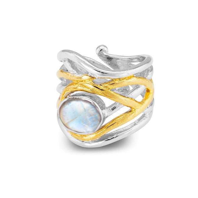 The Mayhem Ring in various gemstones by Gallardo & Blaine Designs features a chunky statement design with a silver and gold intertwined pattern, showcasing a prominent round gemstone. The silver bands act as the base, while gold bands wrap around in a crisscross pattern, giving it a medieval-inspired jewelry feel. The translucent blue gemstone is set prominently in the center.