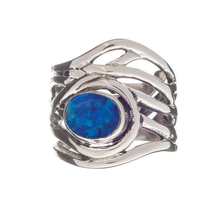 The Mayhem Ring in various gemstones by Gallardo & Blaine Designs features an intricate, wavy band design, set with a central oval blue opal gemstone. This chunky statement ring displays vibrant blue and green hues, adding a bold touch to any medieval-inspired jewelry collection.