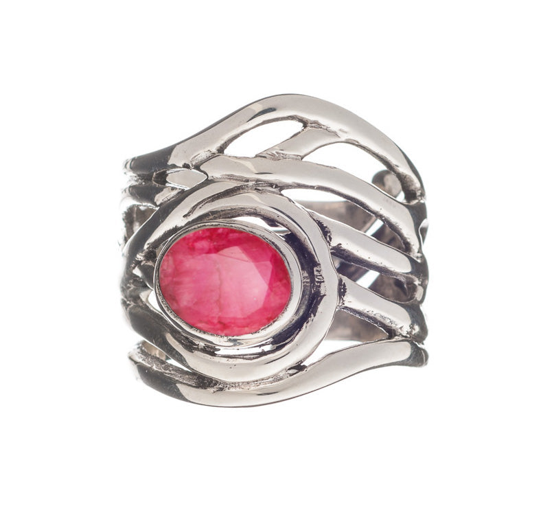 A silver, adjustable ring with an intricate, wavy band design features an oval-shaped, faceted pink gemstone set in the center. The metalwork creates an elegant and modern look, enhancing the vibrant color of the gemstone. This is the Mayhem Ring in various gemstones by Gallardo & Blaine Designs.