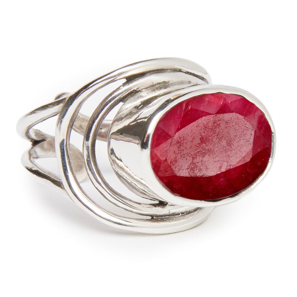 A Party Ring in various gemstones with an intricate, swirling design featuring a large, oval-shaped red gemstone at its center. The faceted gemstone adds a sparkly touch to this statement piece by Gallardo & Blaine Designs, making it a stunning accessory for any occasion.