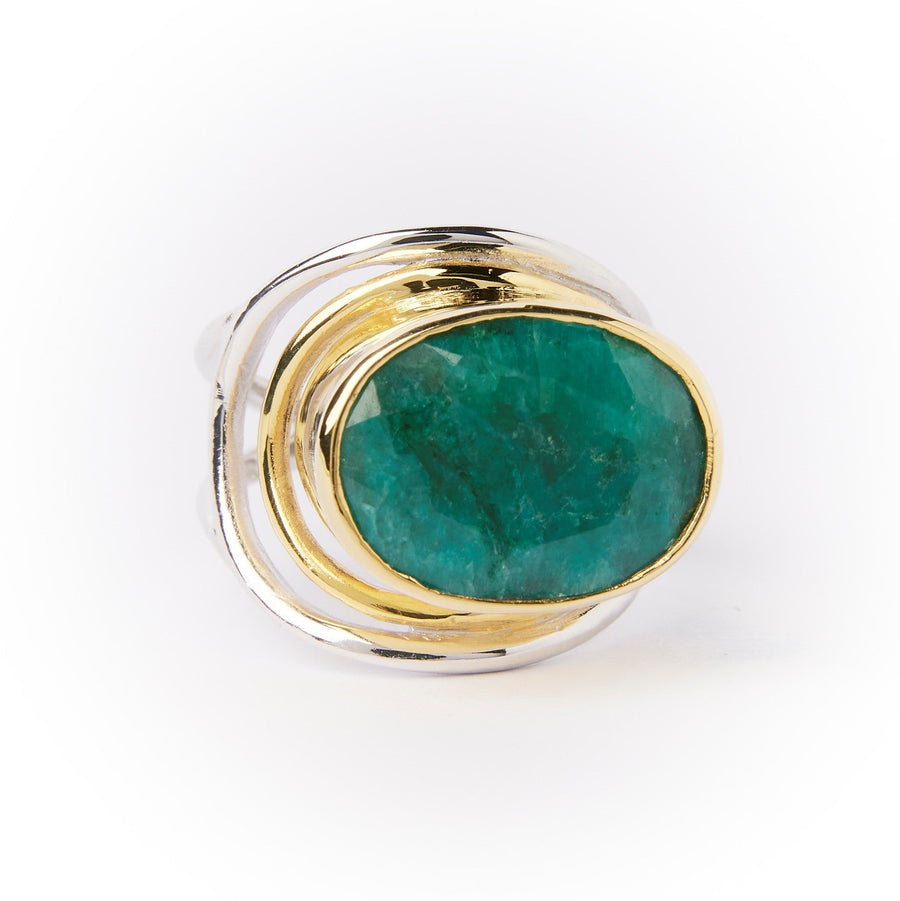 A Party Ring in various gemstones by Gallardo & Blaine Designs with an irregular, swirling design featuring a large, polished green gemstone set in a gold bezel. The statement Party Ring has a smooth, rounded surface, and the shiny silver and gold elements create a layered, intricate look around the central stone.