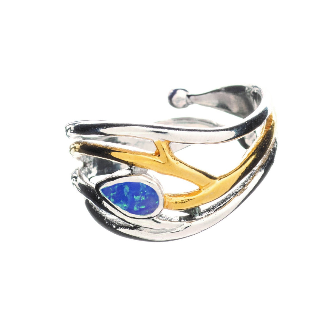 A stylish, adjustable **Peacock Ring in various gemstones** by **Gallardo & Blaine Designs** in silver and gold with an intricate design resembling tree branches. It features a teardrop-shaped blue opal stone as the centerpiece, making it an elegant dainty ring with a touch of nature's beauty.