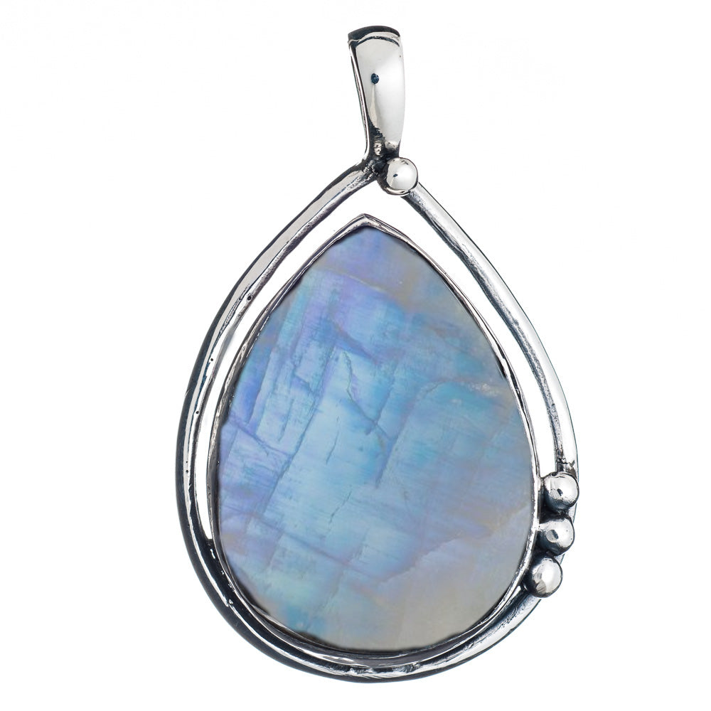 The Poppy Pendant Large in various gemstones by Gallardo & Blaine Designs showcases a teardrop-shaped, iridescent blue and purple labradorite gemstone, elegantly encased in a sterling silver frame with a small silver ball detail on one side. The pendant features a silver bail for attaching to a necklace chain.