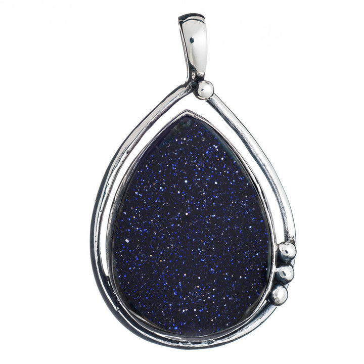 The Poppy Pendant Large in various gemstones from Gallardo & Blaine Designs features a teardrop-shaped blue goldstone, encased in a sleek, sterling silver frame. The blue goldstone sparkles with tiny flecks, giving it a starry night appearance. The minimalistic silver frame includes a small decorative loop and three tiny silver balls.