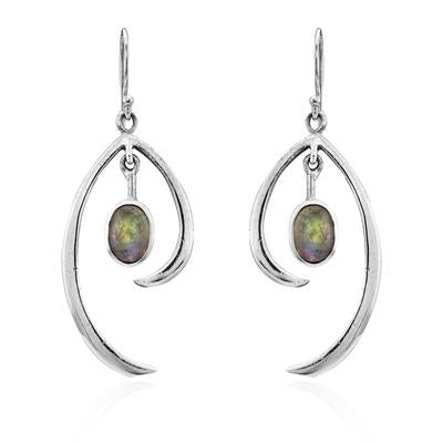 A pair of Primrose Earrings in various gemstones exemplifying minimalist elegance, these sterling silver earrings by Gallardo & Blaine Designs feature an abstract, curved design. Each earring has an oval-shaped gemstone with a dark, iridescent surface suspended within the curvature. Hook-style clasps complete the look against a white background.